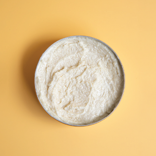 Whipped tallow sugar scrub with yellow background.