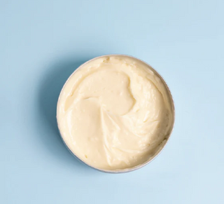 Whipped tallow body butter with blue background.
