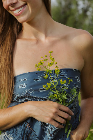Founder of Fatskn Inc., Caitlin Warrington, holding a yellow flower in a pasture.