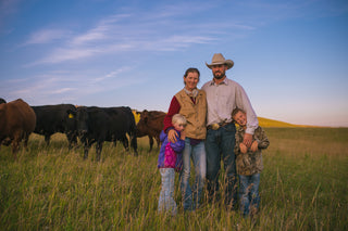 Trails End Beef ranch owners with their kids standing in a pasture with cattle.
